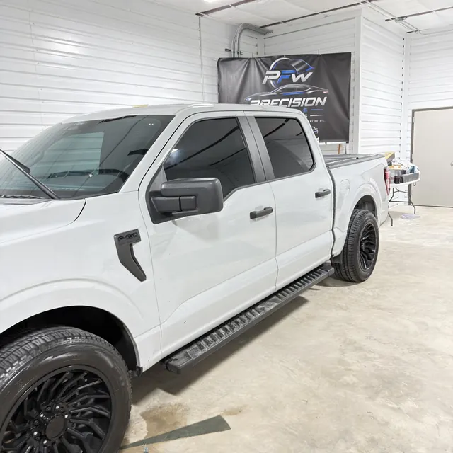 White pickup with tinted windows inside the shop
